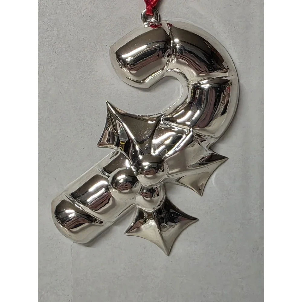 silver-plated Christmas ornament shaped like a candy cane with a holly design